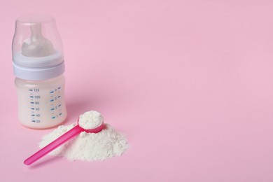 Photo of Powdered infant formula with scoop and feeding bottle on pink background, space for text. Baby milk