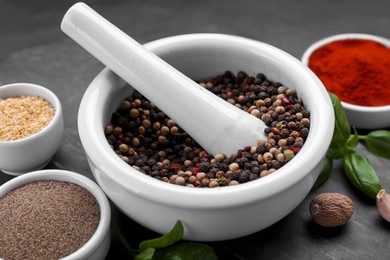 Photo of Mortar with pestle and different spices on black table, closeup