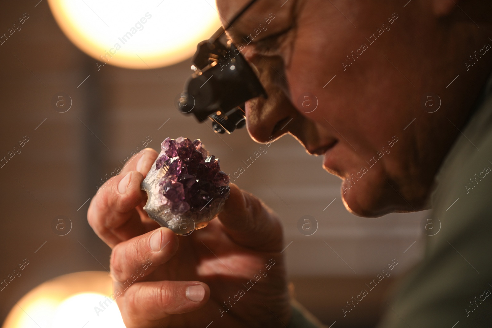 Photo of Professional jeweler working with beautiful amethyst indoors, closeup