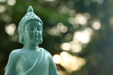 Decorative Buddha statue on blurred background outdoors, closeup. Space for text