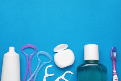 Tongue cleaners and other oral care products on blue background, flat lay. Space for text