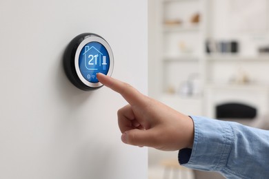 Image of Smart home system. Woman using thermostat indoors, closeup
