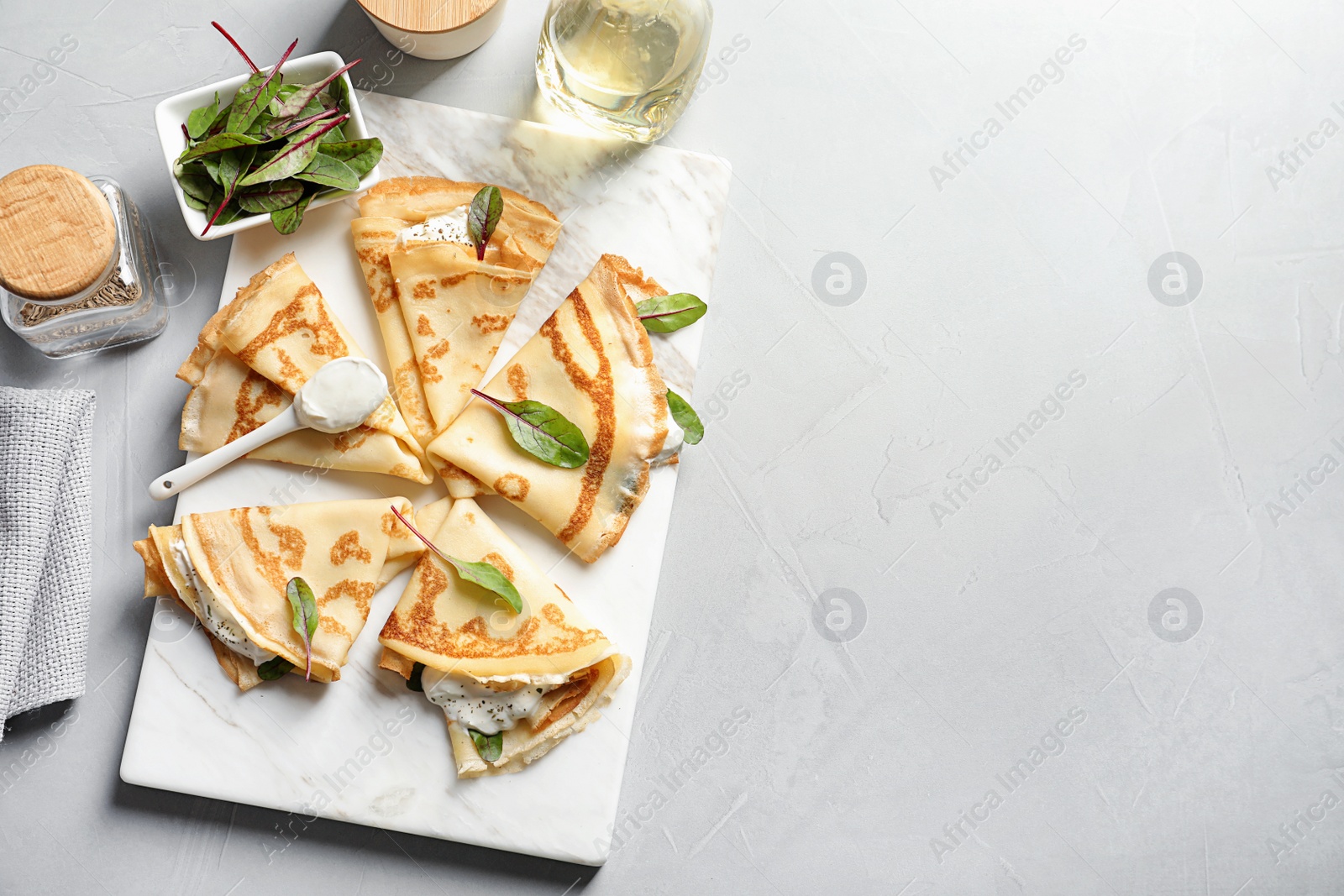 Photo of Thin pancakes with sour cream on board, top view