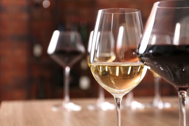 Photo of Tasty red and white wines in glasses against blurred background, space for text