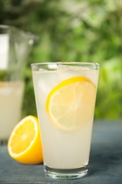 Photo of Cool freshly made lemonade in glass on blue table