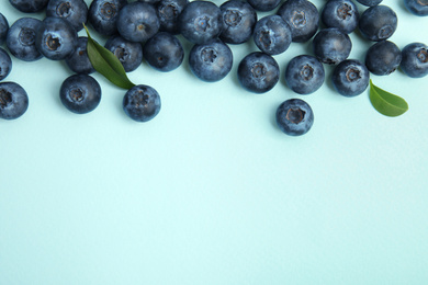 Photo of Fresh ripe blueberries on light blue background, flat lay. Space for text