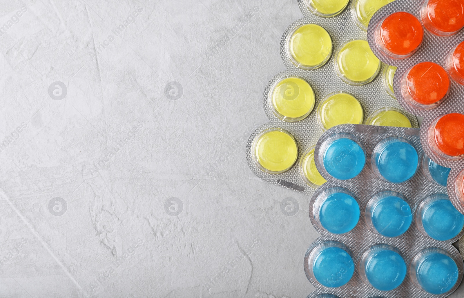 Photo of Blisters with color cough drops on grey background, top view. Space for text