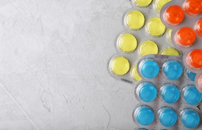 Blisters with color cough drops on grey background, top view. Space for text