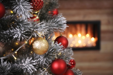 Closeup view of decorated Christmas tree in room, space for text. Festive interior