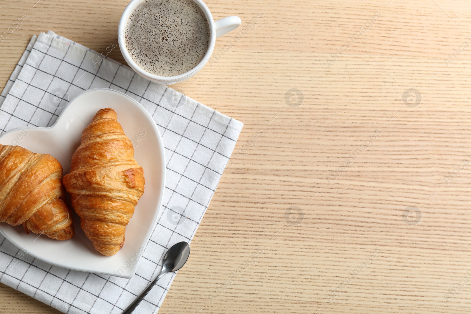 Photo of Plate of fresh croissants served on wooden table, flat lay with space for text. French pastry