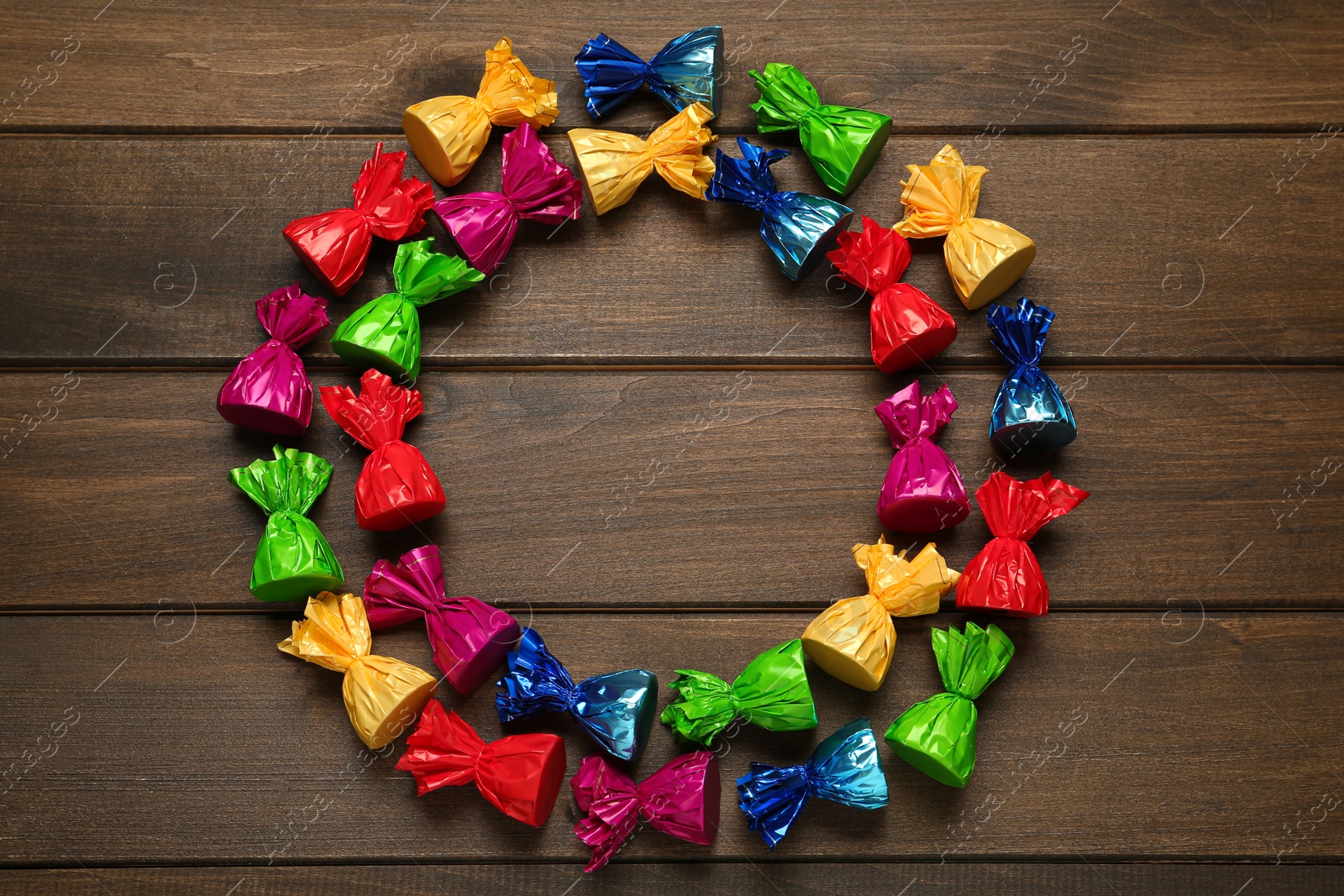 Photo of Frame of candies in colorful wrappers on wooden table, flat lay. Space for text