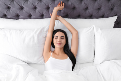 Photo of Young woman awakening at home, top view. Lazy morning