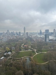 Photo of Picturesque view of city with modern buildings and park on cloudy day