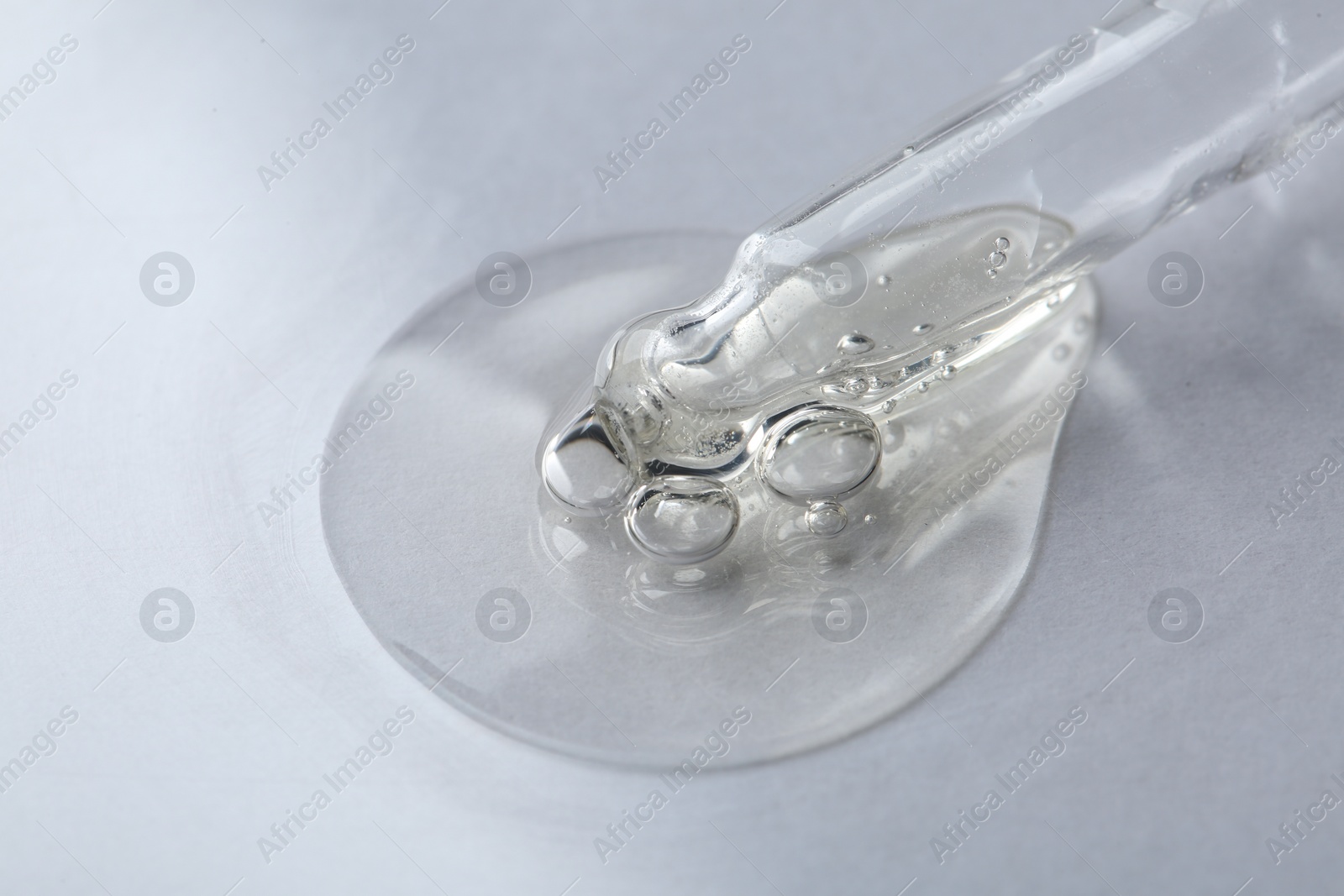 Photo of Pipette with cosmetic serum on white background, macro view