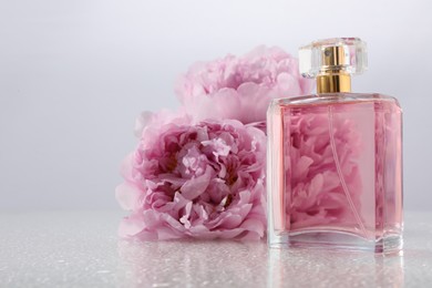 Photo of Luxury perfume and floral decor on plastic surface, space for text