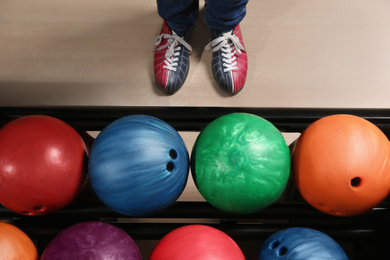 Photo of Person in bowling shoes near rack with balls, top view