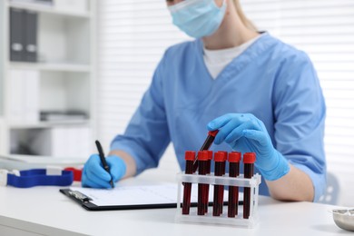 Photo of Laboratory testing. Doctor with blood samples in tubes at white table indoors