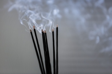 Incense sticks smoldering on grey background, closeup