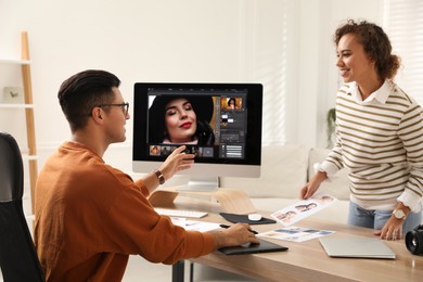 Professional retoucher with colleague working at desk in office