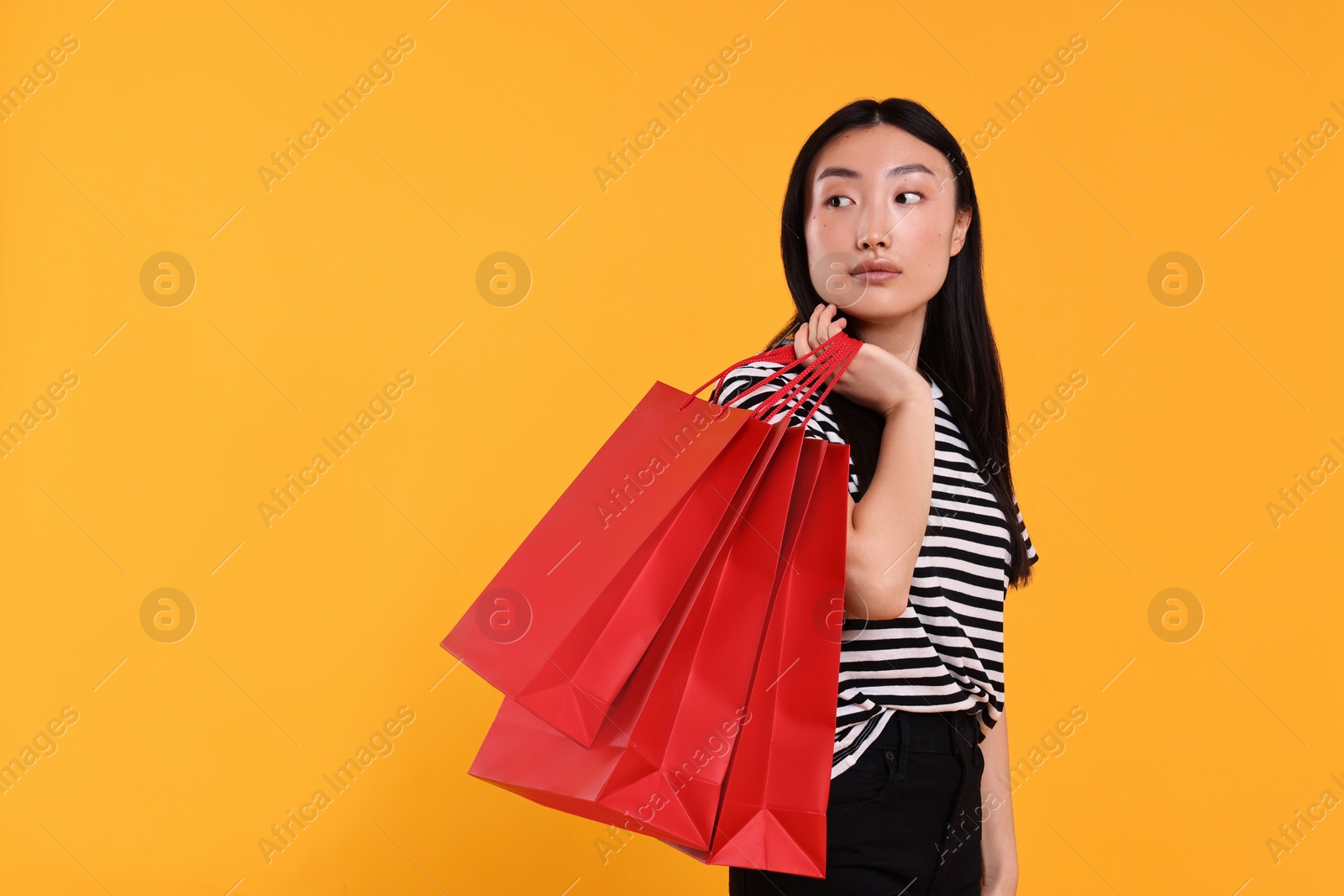 Photo of Beautiful woman with shopping bags on yellow background. Space for text