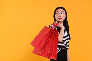 Beautiful woman with shopping bags on yellow background. Space for text