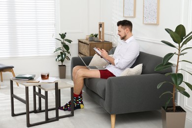 Photo of Businessman wearing shirt and underwear during video call at home