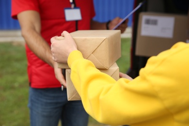 Photo of Courier giving packages to customer outdoors, closeup