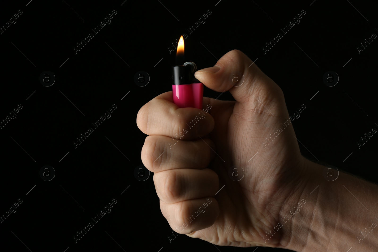 Photo of Man holding pink lighter on black background, closeup