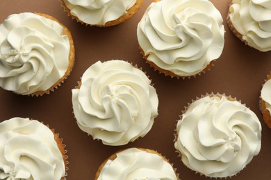 Tasty vanilla cupcakes with cream on dark beige background, top view