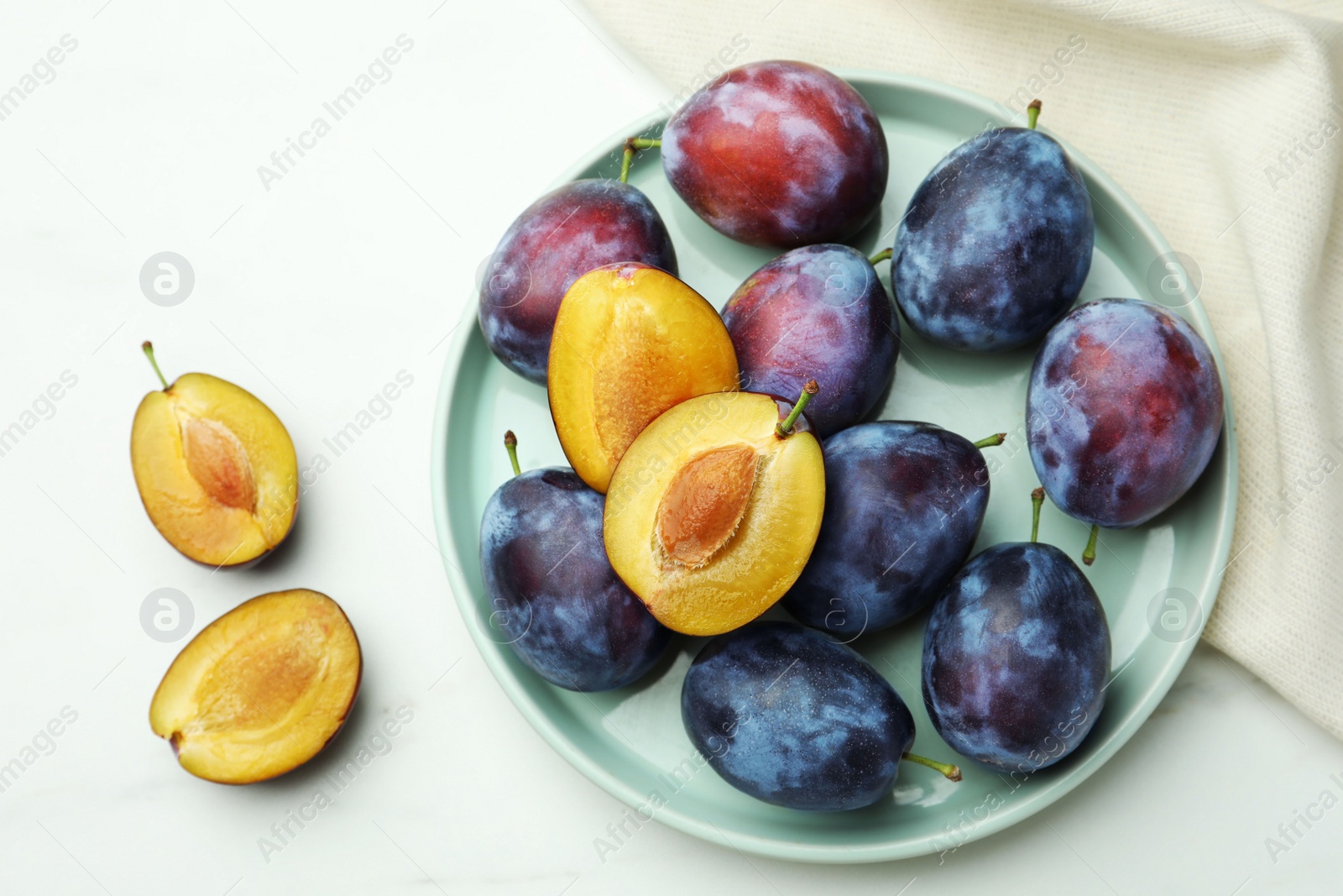 Photo of Tasty ripe plums on white table, flat lay