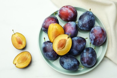Tasty ripe plums on white table, flat lay