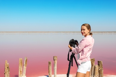 Professional photographer taking photo of pink lake on sunny day
