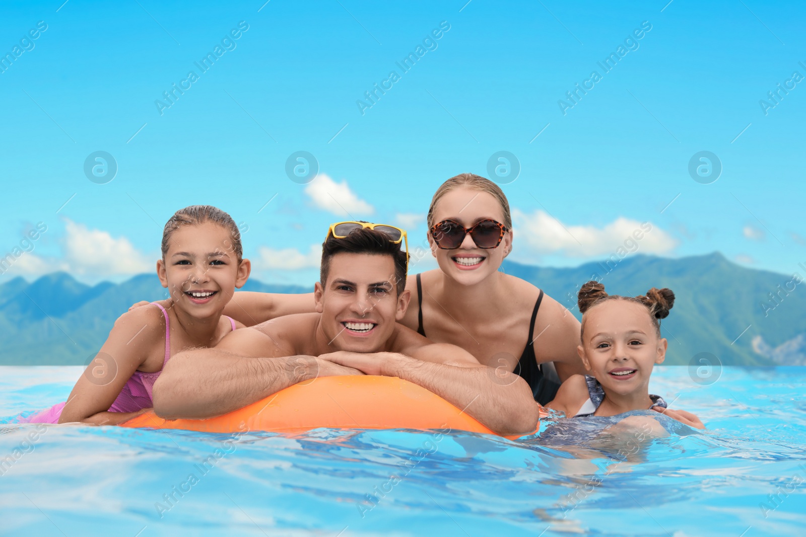 Image of Happy family in outdoor swimming pool at luxury resort with beautiful view of mountains on sunny day