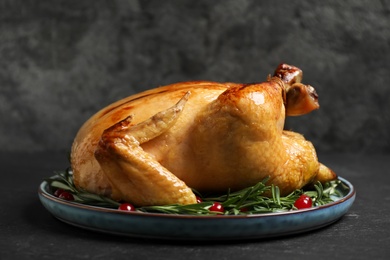 Photo of Delicious cooked turkey served with rosemary and cranberries on black table. Thanksgiving Day celebration