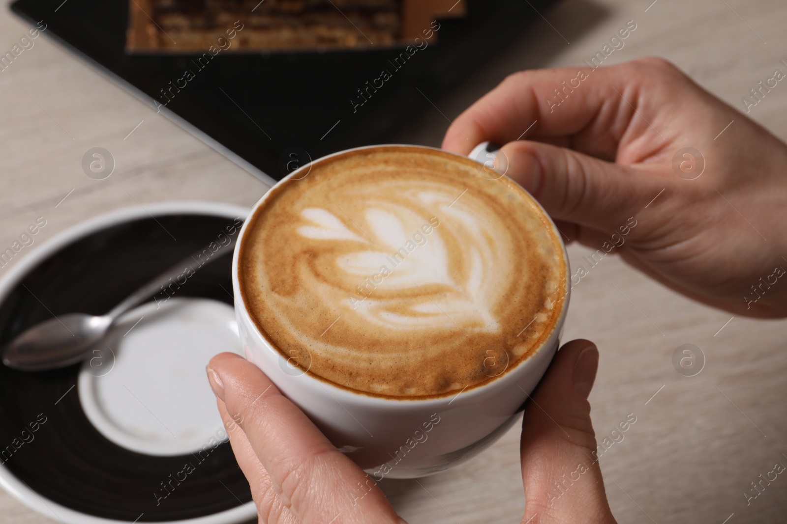 Photo of Woman with cup of aromatic coffee at table, closeup