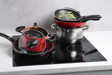 Photo of Stacks of dirty kitchenware on cooktop in kitchen