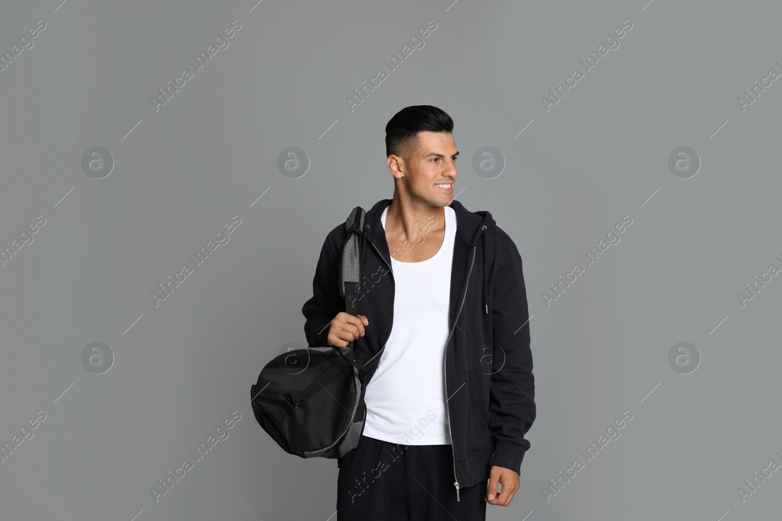 Photo of Handsome man with sports bag on grey background