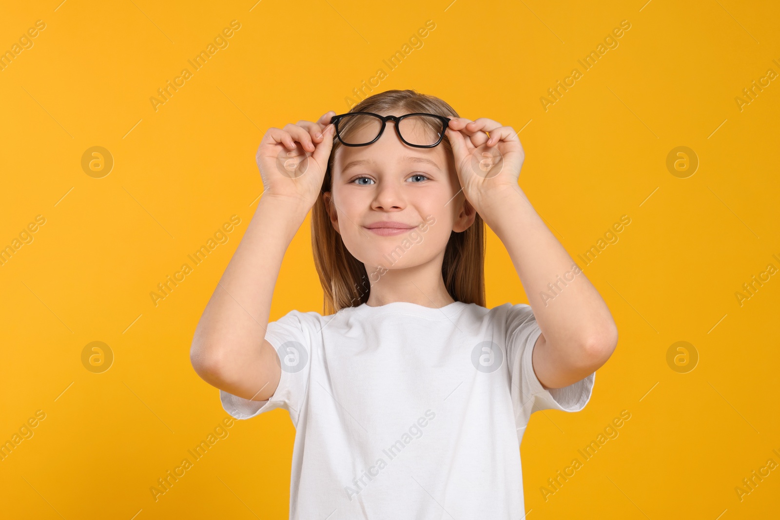 Photo of Portrait of cute girl with glasses on orange background