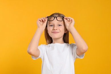 Photo of Portrait of cute girl with glasses on orange background