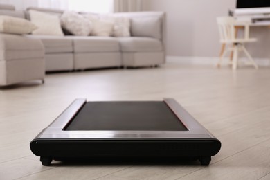 Photo of Modern walking treadmill in living room. Home gym equipment