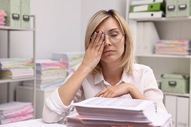 Photo of Overwhelmed woman at table with documents in office