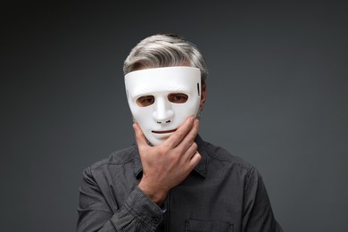 Photo of Multiple personality concept. Man in mask on dark grey background