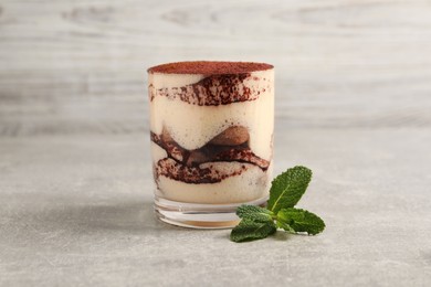 Delicious tiramisu in glass and mint on grey textured table