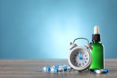 Alarm clock and insomnia remedies on wooden table. Space for text