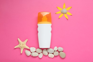 Photo of Suntan cream, sun made of paper and seashells on pink background, flat lay