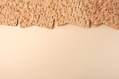 Photo of Fresh crunchy crispbreads on beige background, flat lay. Space for text