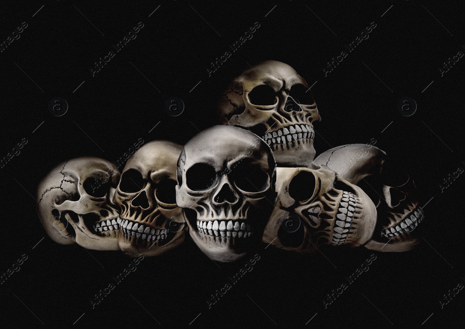 Image of Pile of scary human skulls on black background