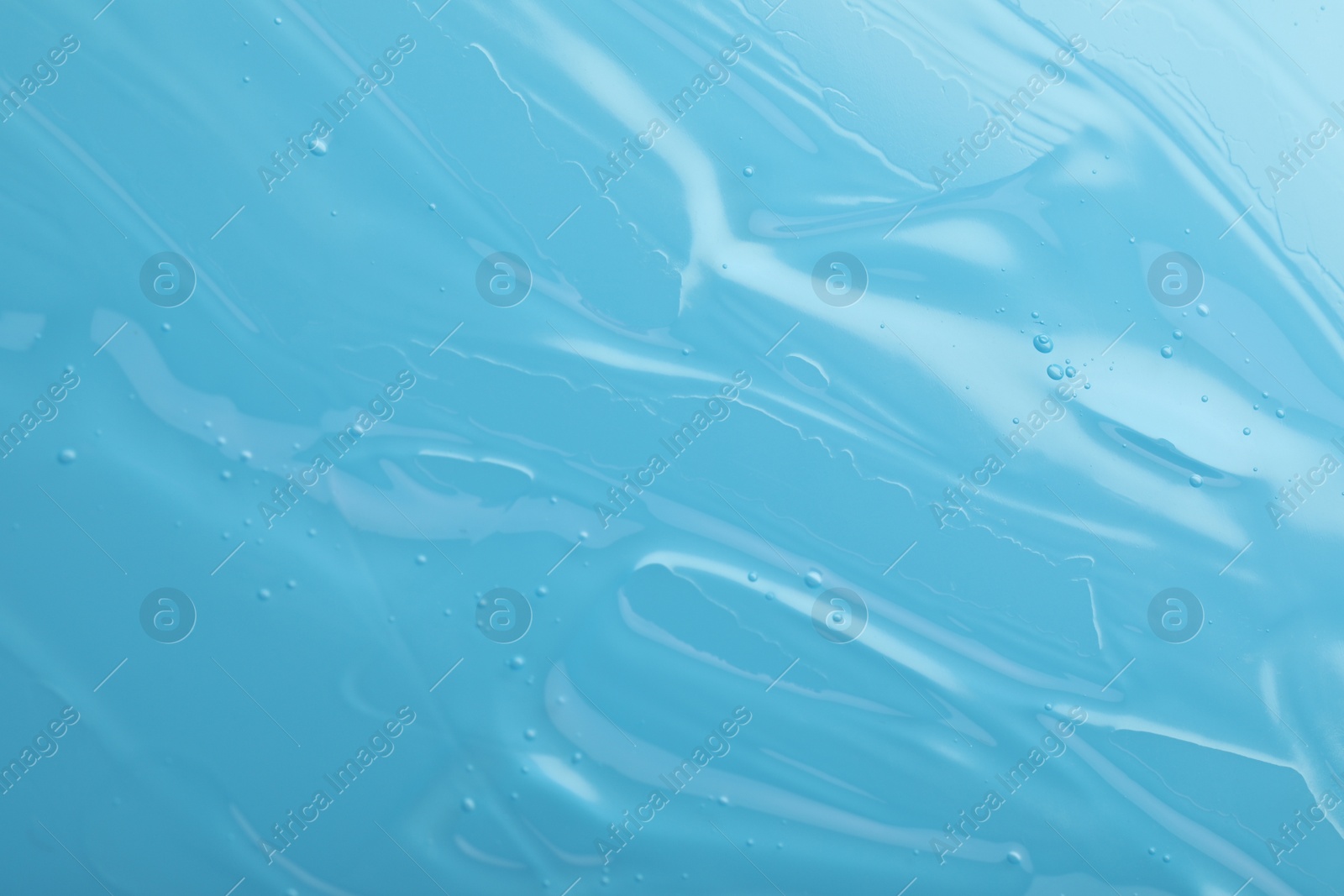 Photo of Pure transparent cosmetic gel on light blue background, closeup