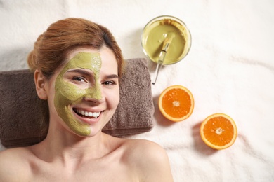 Photo of Beautiful woman with mask on face relaxing in spa salon, top view