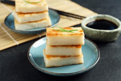 Photo of Delicious turnip cake with herb and soy sauce on black table